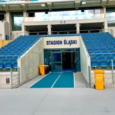 Puste niebieskie trybuny stadionu Śląskiego w Chorzowie, z wejściem na arenę.