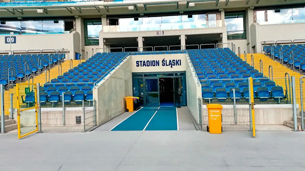 Puste niebieskie trybuny stadionu śląskiego chorzów, z wejściem na środek.